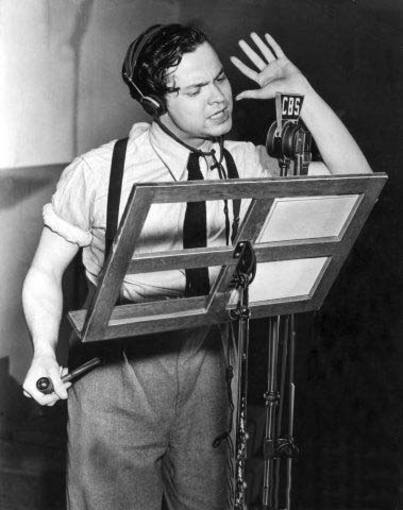 Fotografía histórica de Orson Welles con auriculares dirigiendo la transmisión dramática de La Guerra de los Mundos ante los micrófonos de la emisora CBS en 1938